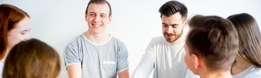 Alcohol Rehab in Colorado - A group of young adults hold hands during their group therapy session at the alcohol rehab in Colorado.