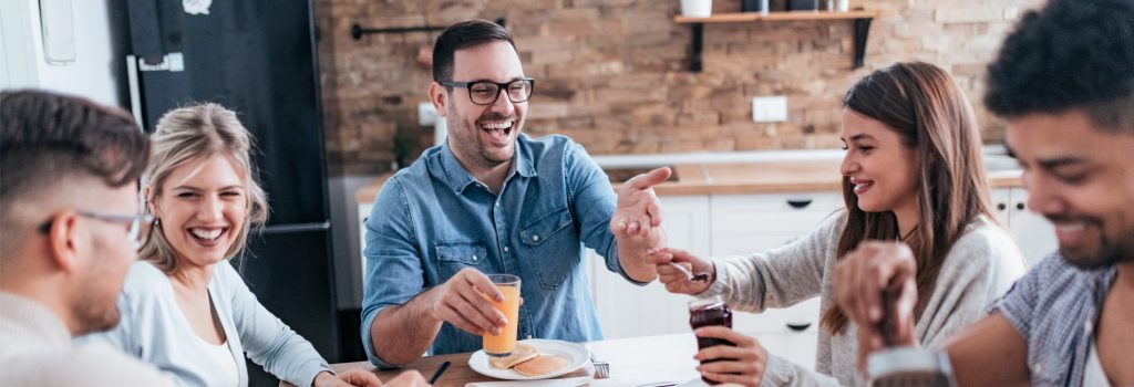 Residential Rehab - A group laughs over breakfast at the home they share during residential rehab for addiction before going over the rehab center for the day.
